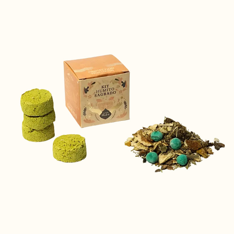 A small smudge kit with green charcoal briquettes, brown aromatic pearls, herbs, and resins next to its packaging box with the brand name Sagrada Madre.
